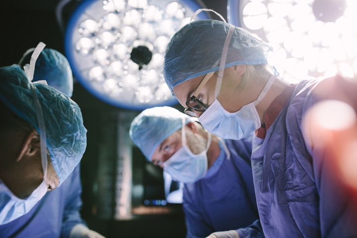 Concentrated surgeon performing surgery with her team Healthcare copywriter represented by a surgeon in an operating theatre