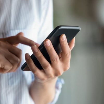 Close up woman holding smartphone in hand, typing on screen Email copywriter represented by a woman holding a phone.