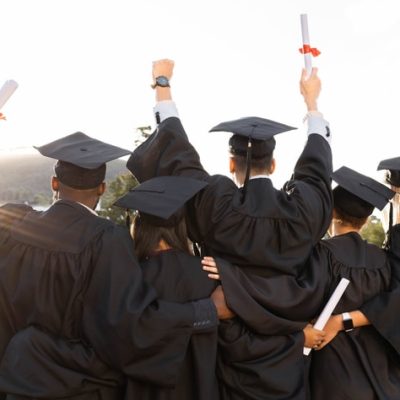 Graduation, group and back view of students celebrate education success. Behind of excited graduates at campus celebration for study goals, university award and learning motivation for happy future Copywriter for universities represented by a photo of a group of graduates on graduation day