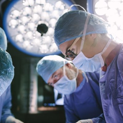 Concentrated surgeon performing surgery with her team Healthcare copywriter represented by a surgeon in an operating theatre